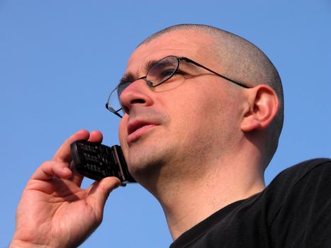 Young bald-headed man speking to the mobile phone          