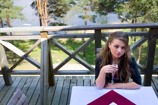Young girl with glass of champagne on veranda