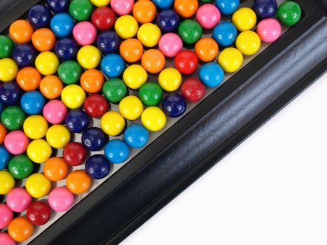 A colorful variety of gumballs in a close but random pattern in a black frame, with room for text.