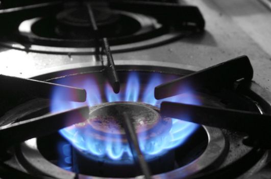 The blue flames of a gas powered stove top symbolize energy used for household purposes