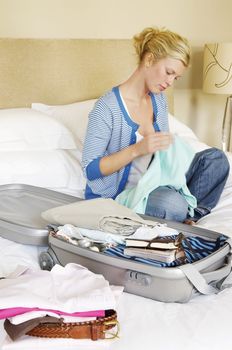 Woman Packing Suitcase on Bed
