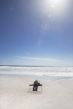 Businessman Sitting at an Office Desk at the Beach