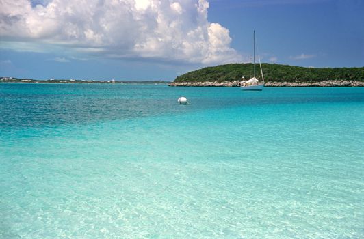 A sailboat is moored on the tropical turquoise water of the Bahamas