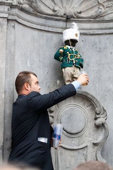 BRUSSELS - OCTOBER 3: Manneken Pis dressed in uniform of Fanfare Royale de Moulbaix-Ligne and urinating beer, Brussels, Belgium October 3, 2009