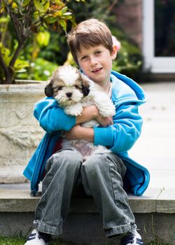 Young boy holding a lhasa apso puppy