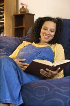 Pregnant smiling woman reading.