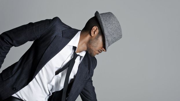 Male model poses in suit with his fedora over his face