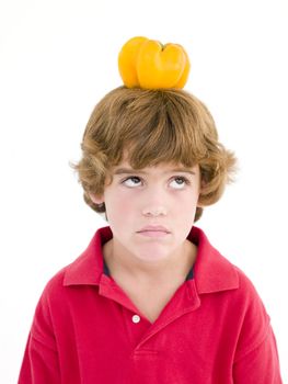 Young boy with yellow pepper on his head frowning