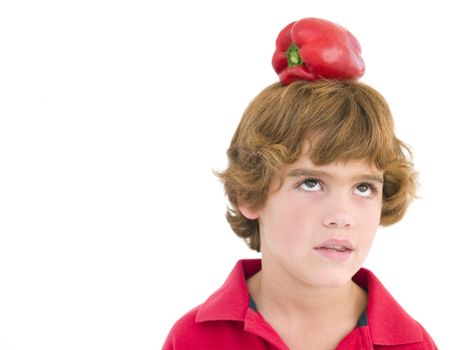 Young boy with red pepper on his head frowning