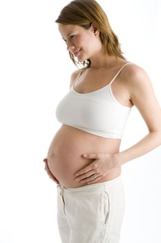 Pregnant woman holding exposed belly smiling