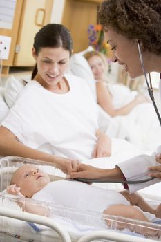 Doctor checking baby's heartbeat with new mother watching and sm