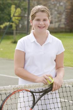 Young girl with racket on tennis court smiling