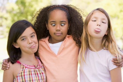 Three young girl friends outdoors making funny faces