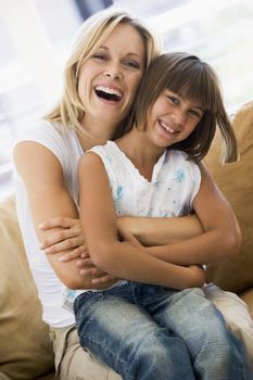 Woman and young girl sitting in living room smiling