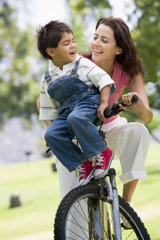 Woman and young boy on a bike outdoors smiling