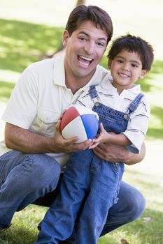 Man and young boy outdoors with football smiling