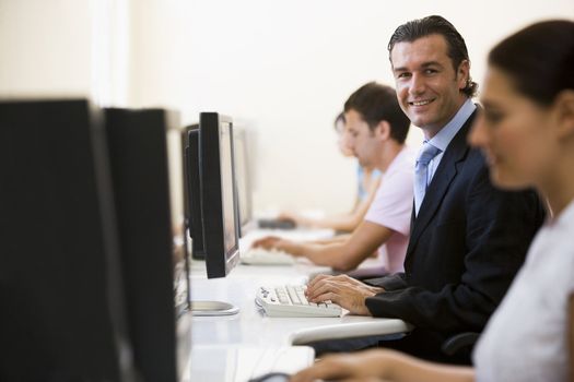 Four people in computer room with one man wearing a suit smiling
