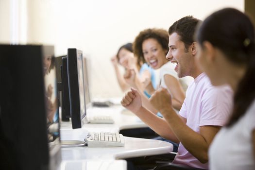 Four people in computer room cheering and smiling