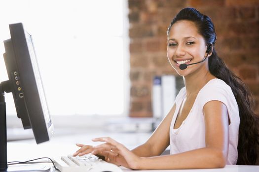 Businesswoman in office wearing headset and typing on computer s