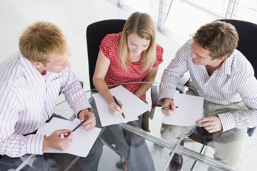Three businesspeople in boardroom with paperwork