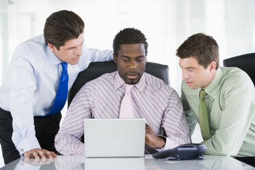 Three businessmen in a boardroom looking at laptop
