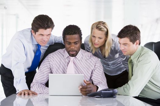 Four businesspeople in a boardroom looking at laptop
