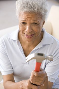 Woman holding hammer looking unsure