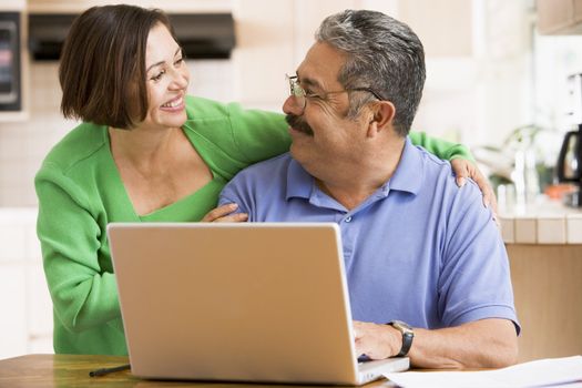 Couple in kitchen with laptop smiling