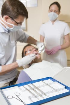 Dentist and assistant in exam room with man in chair