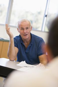 Mature male student gesturing in class