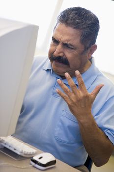 Mature male student expressing frustration at computer