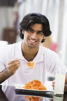 Man at restaurant eating sandwich and smiling