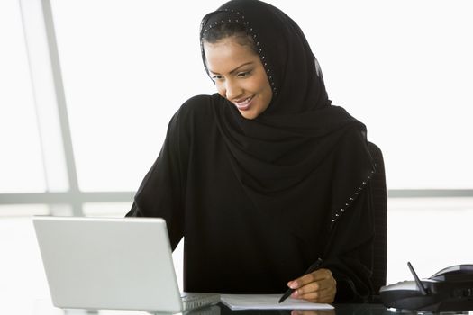 Businesswoman in office with laptop thinking 