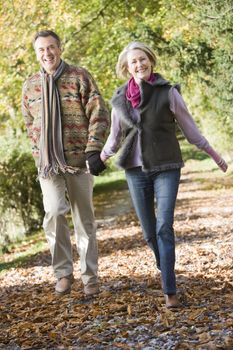 Couple outdoors walking on path in park holding hands and smiling