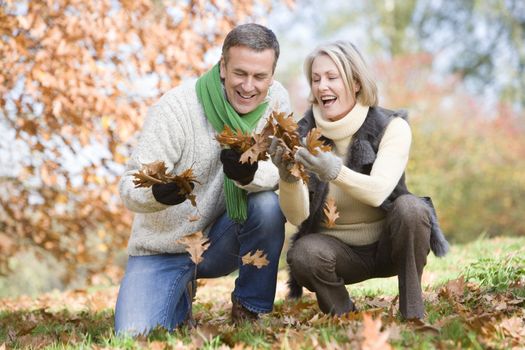 Couple outdoors looking at leaves and smiling