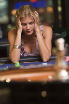 Woman in casino playing roulette and thinking 