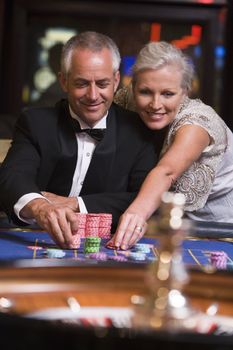 Couple in casino playing roulette and smiling