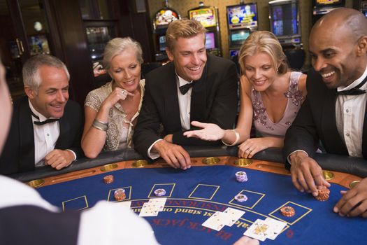Five people in casino playing blackjack and smiling