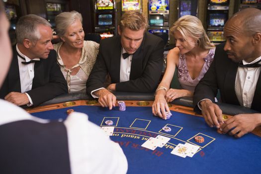Five people in casino playing blackjack and smiling