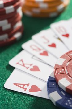 Playing cards making royal flush in hearts by poker chips