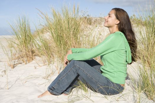 Young woman sitting in sand dunes