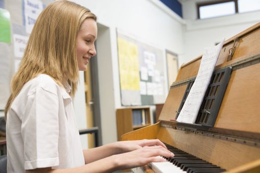 Female student learning piano in classroom 