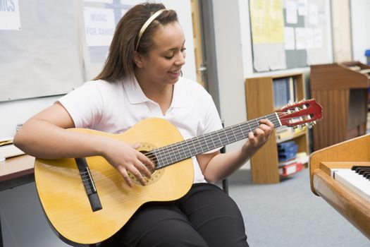 Female student learning guitar in classroom 