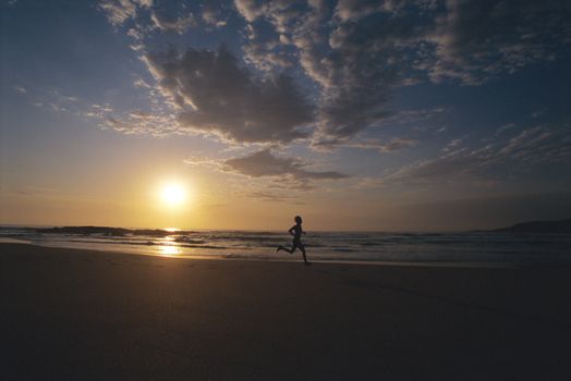 Man outdoors running on a beach at sunset (silhouette) 