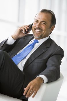 Businessman sitting indoors on cellular phone (high key/selective focus) 