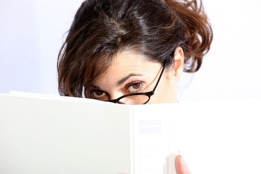 A young woman hides behind a folder / book 