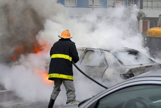Firefighter extinguishing a car fire. Last stage of a fire