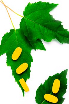 yellow vitamin pills over green leaves