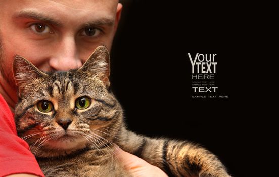 Man holding tabby cat with big green eyes