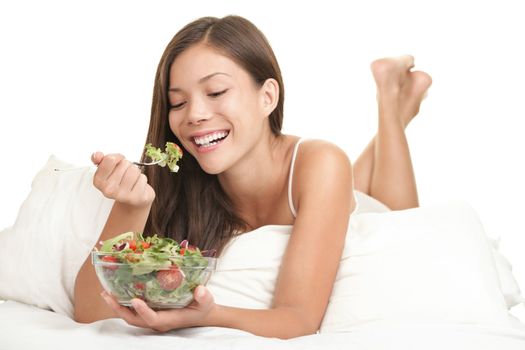 Healthy woman eating salad in bed